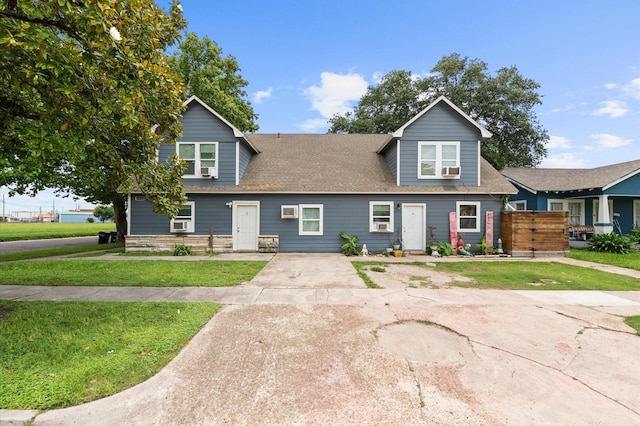 view of front of home with an AC wall unit and a front lawn