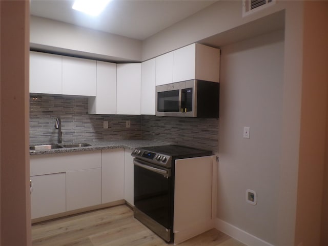 kitchen featuring sink, stainless steel appliances, white cabinets, and backsplash