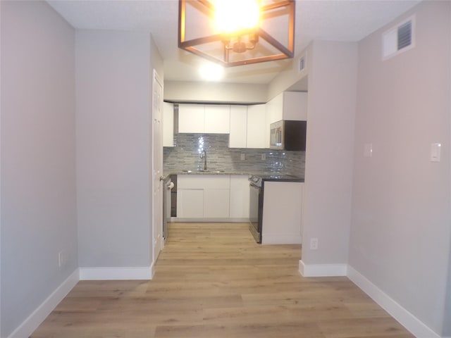 kitchen featuring stainless steel appliances, white cabinets, light hardwood / wood-style flooring, backsplash, and sink