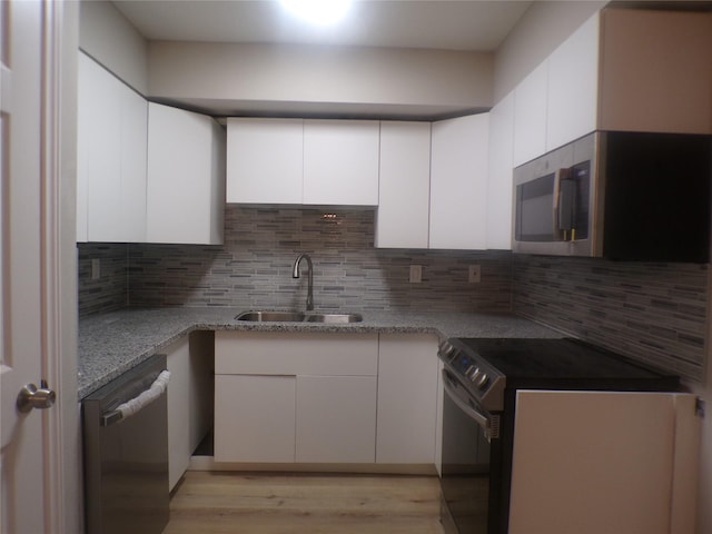 kitchen featuring stainless steel appliances, white cabinetry, and decorative backsplash