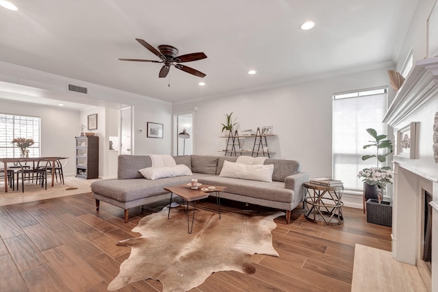 living room with a fireplace, ceiling fan, and crown molding