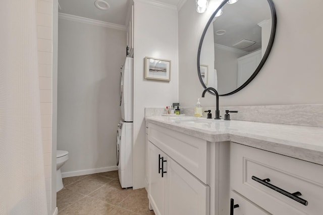 bathroom featuring vanity, stacked washer and clothes dryer, crown molding, tile patterned flooring, and toilet