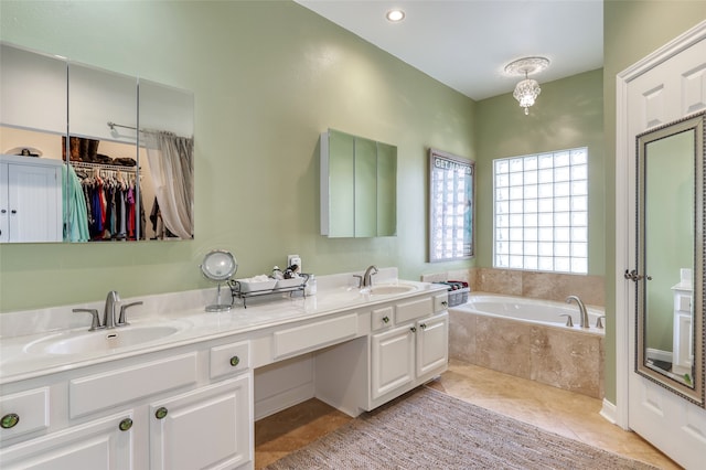 bathroom with tile patterned flooring, vanity, and tiled tub