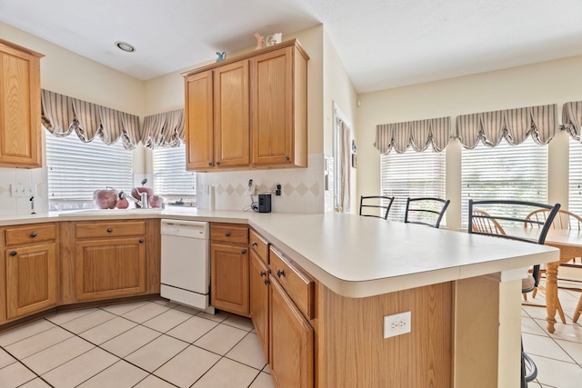 kitchen featuring light tile patterned floors, backsplash, and dishwasher