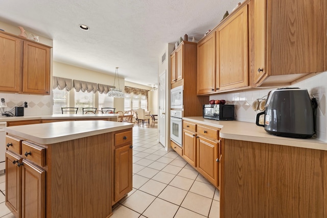 kitchen featuring pendant lighting, tasteful backsplash, light tile patterned floors, white appliances, and a kitchen island