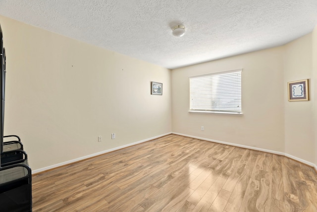 unfurnished room with a textured ceiling and light wood-type flooring