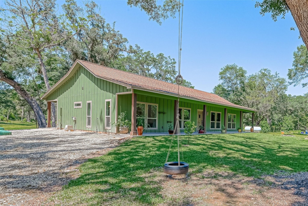 view of front of property with driveway, a shingled roof, a porch, board and batten siding, and a front yard