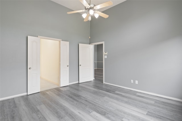 unfurnished bedroom featuring a high ceiling, light hardwood / wood-style flooring, and ceiling fan