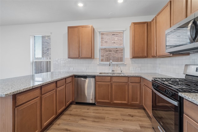 kitchen with sink, light wood-type flooring, backsplash, kitchen peninsula, and stainless steel appliances