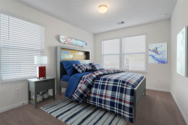 bedroom featuring dark colored carpet and a textured ceiling