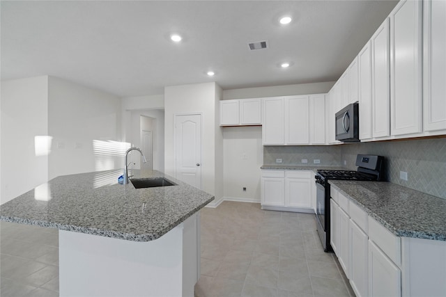 kitchen featuring a kitchen island with sink, sink, white cabinets, and stainless steel gas range