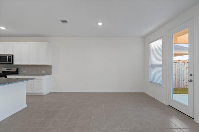 kitchen featuring white cabinets, decorative backsplash, gas stove, and light tile patterned floors