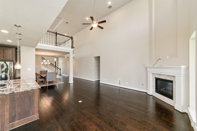 living room featuring dark wood-type flooring, a high ceiling, and a tiled fireplace