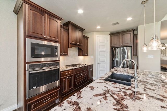 kitchen featuring dark brown cabinets, stainless steel appliances, decorative light fixtures, and sink