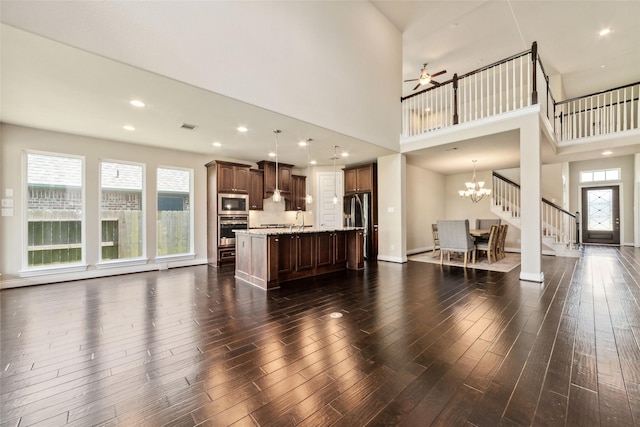 living room featuring dark hardwood / wood-style floors, sink, a towering ceiling, and ceiling fan with notable chandelier