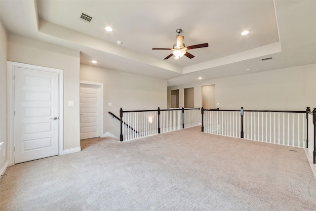 carpeted empty room featuring a tray ceiling and ceiling fan