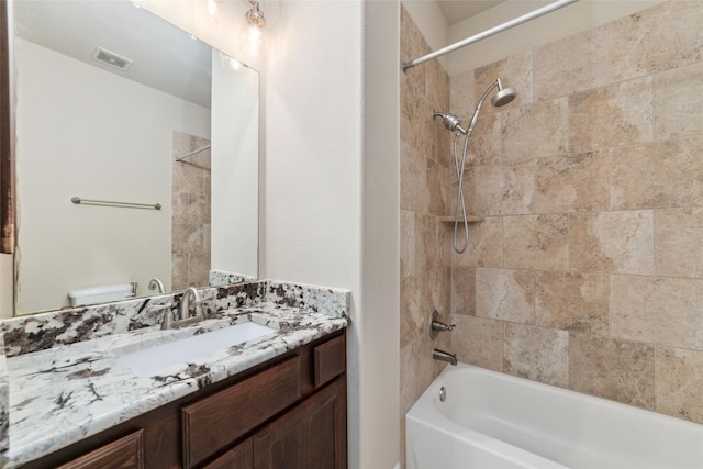 full bathroom featuring vanity, tiled shower / bath combo, and toilet