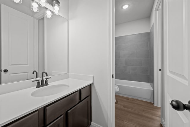 full bathroom featuring hardwood / wood-style floors, tiled shower / bath combo, toilet, and vanity