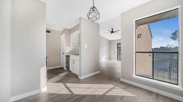 interior space featuring tasteful backsplash, a healthy amount of sunlight, decorative light fixtures, and white cabinets