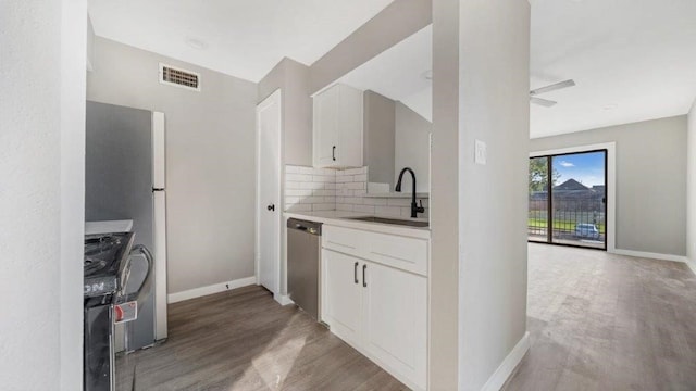 kitchen with sink, white cabinetry, appliances with stainless steel finishes, hardwood / wood-style flooring, and backsplash