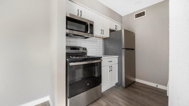 kitchen with backsplash, stainless steel appliances, hardwood / wood-style floors, and white cabinets