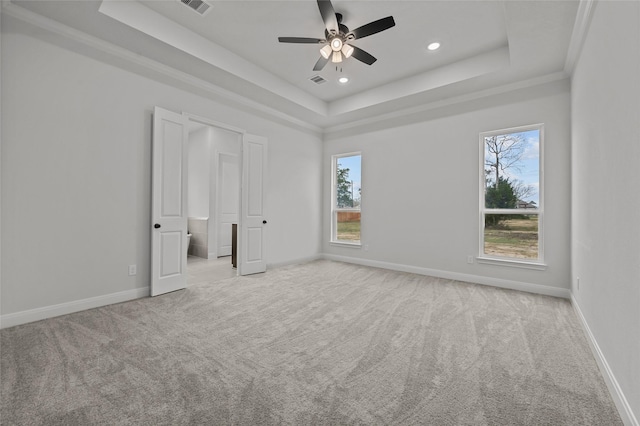 unfurnished bedroom featuring ceiling fan, multiple windows, and a raised ceiling