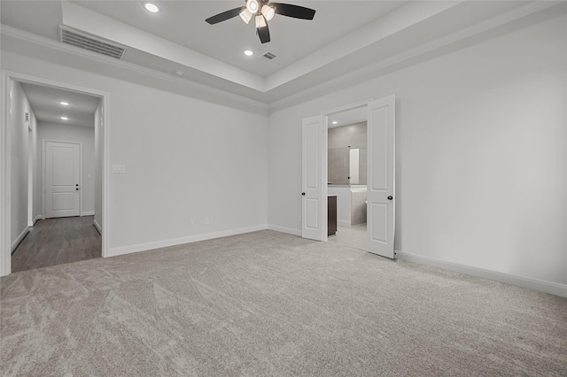 unfurnished room featuring ceiling fan, a tray ceiling, and light carpet