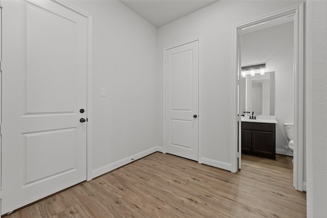 unfurnished bedroom featuring sink, light hardwood / wood-style floors, and connected bathroom