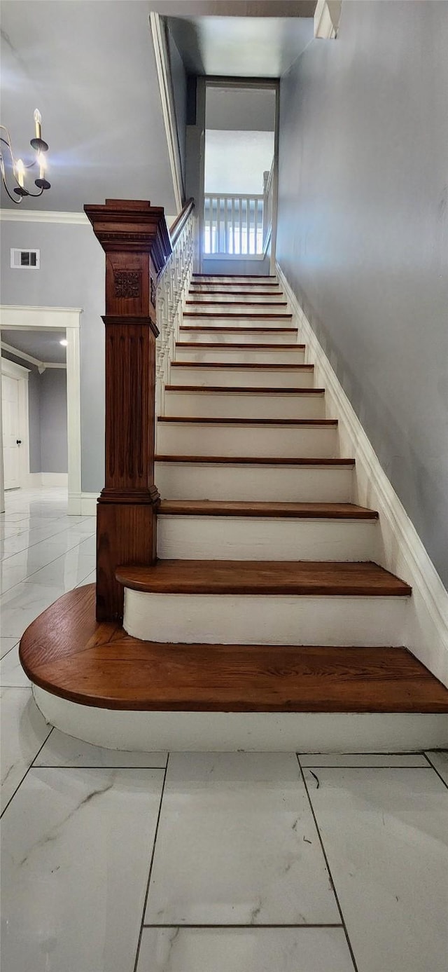 stairway featuring a chandelier and crown molding