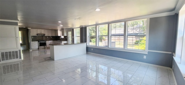 kitchen featuring backsplash, plenty of natural light, dark stone countertops, and stainless steel electric range