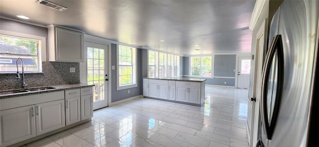 kitchen featuring backsplash, plenty of natural light, sink, and stainless steel refrigerator