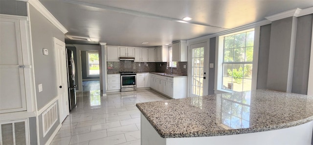 kitchen featuring white cabinets, sink, light stone countertops, appliances with stainless steel finishes, and tasteful backsplash