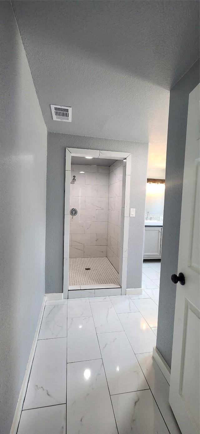 bathroom featuring a textured ceiling and tiled shower