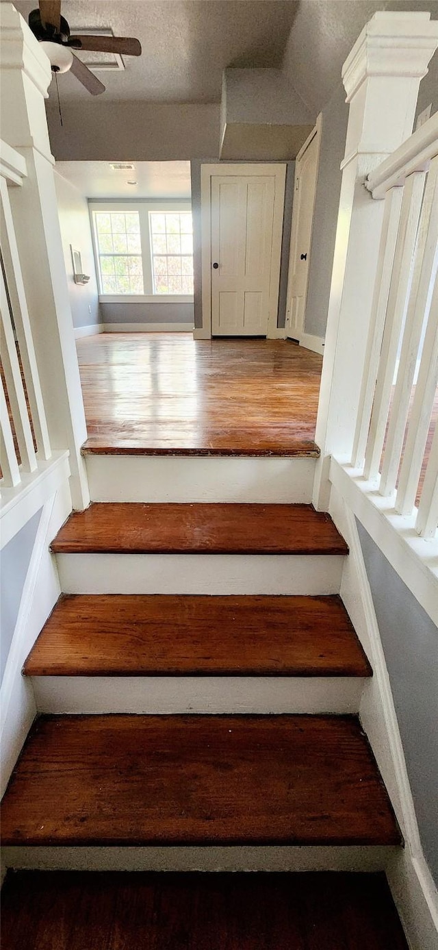 stairs featuring hardwood / wood-style flooring and ceiling fan