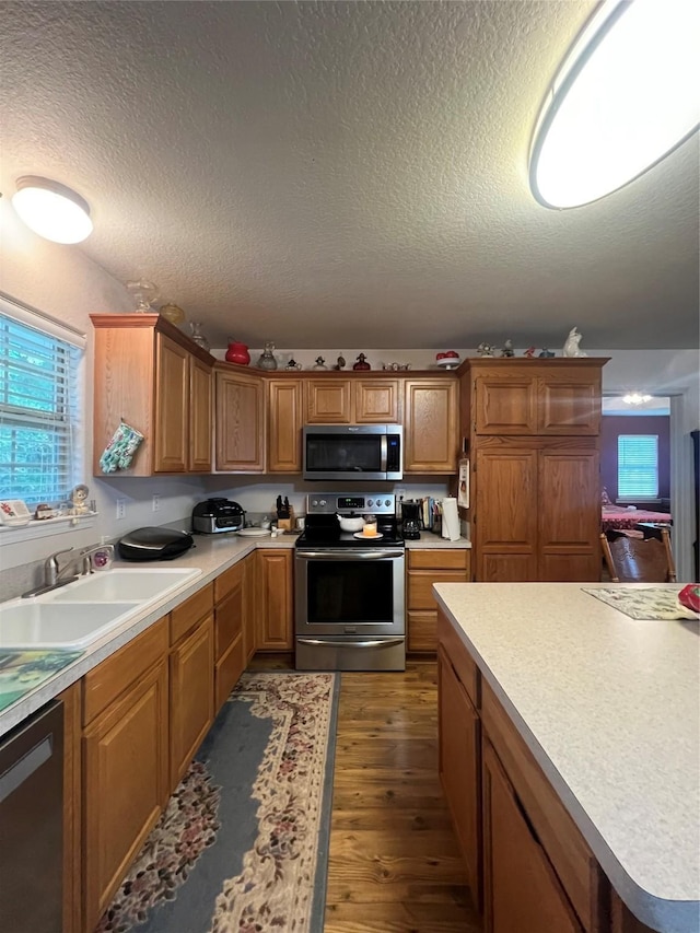 kitchen with a textured ceiling, sink, dark hardwood / wood-style floors, and appliances with stainless steel finishes