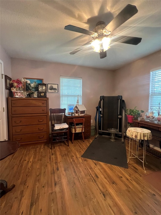 interior space with ceiling fan, a textured ceiling, and hardwood / wood-style flooring