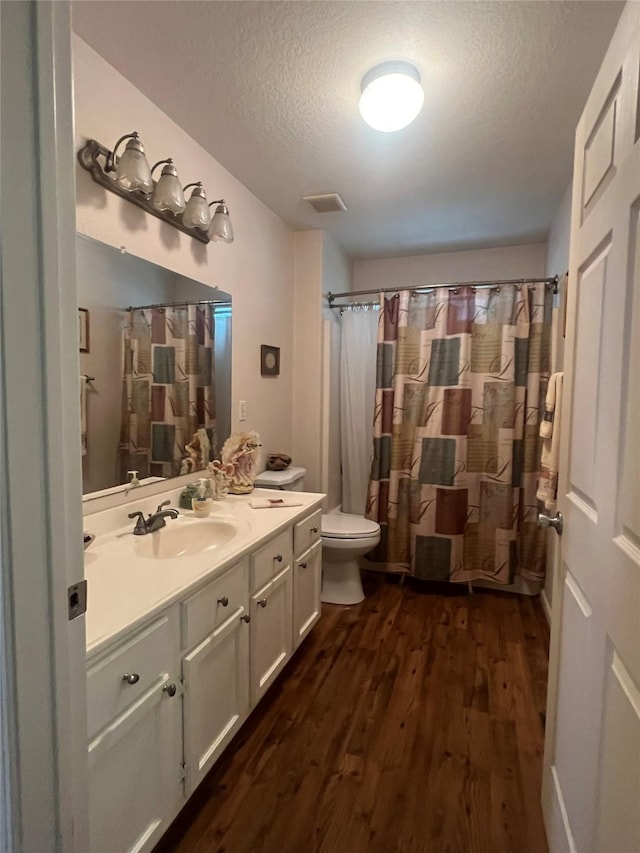 bathroom with hardwood / wood-style floors, vanity, toilet, and a textured ceiling