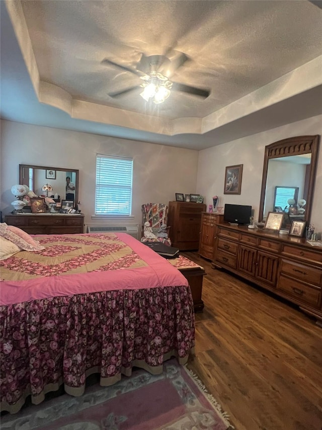 bedroom featuring wood-type flooring, a textured ceiling, a raised ceiling, and ceiling fan