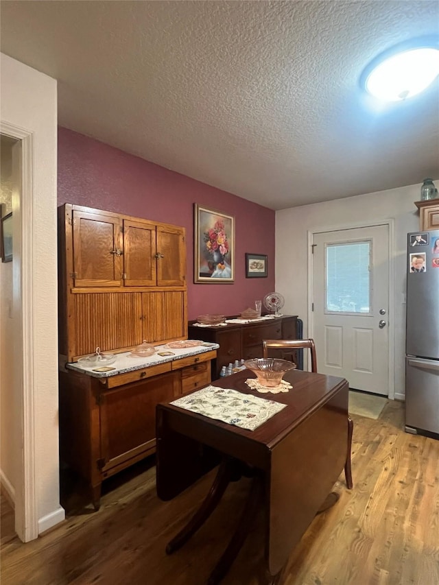 dining room with a textured ceiling and light hardwood / wood-style floors