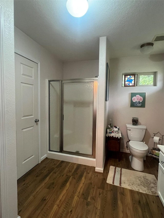 bathroom featuring toilet, an enclosed shower, and wood-type flooring