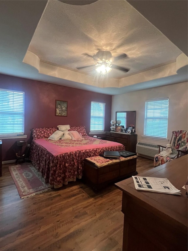 bedroom with ceiling fan, wood-type flooring, and a tray ceiling