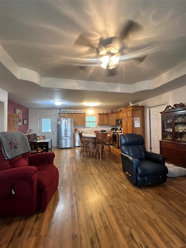 living room featuring ceiling fan, a textured ceiling, and hardwood / wood-style flooring