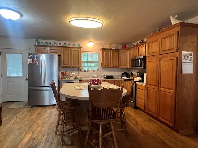 kitchen featuring a center island, a textured ceiling, stainless steel appliances, and light hardwood / wood-style floors