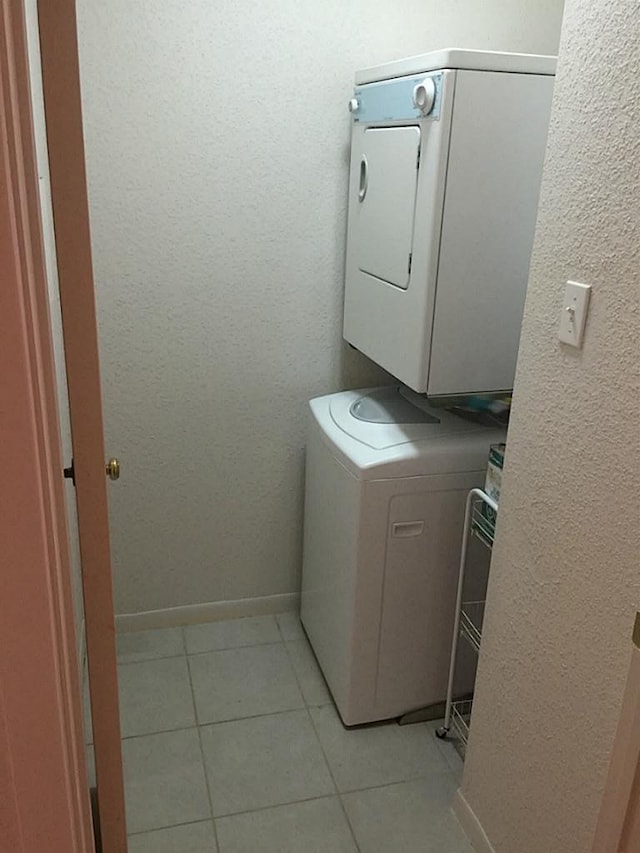 laundry room featuring light tile patterned floors and stacked washer / dryer