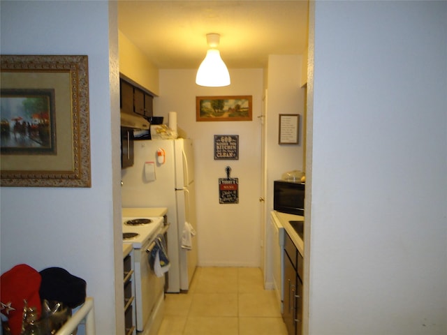 kitchen with dark brown cabinets, light tile patterned floors, and white appliances