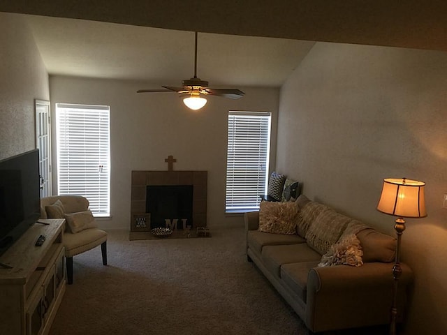 living room featuring a tiled fireplace, ceiling fan, and carpet