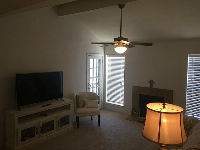 carpeted living room featuring ceiling fan, a tiled fireplace, and vaulted ceiling