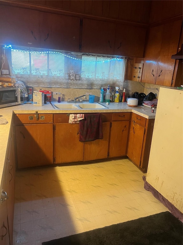 606 E Humble St, Baytown, TX 77520 - kitchen featuring light countertops, stainless steel microwave, light floors, and a sink