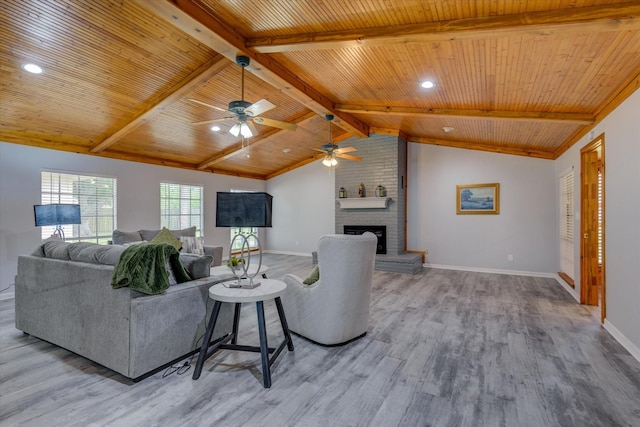 living room featuring vaulted ceiling with beams, light wood-type flooring, a fireplace, and wooden ceiling