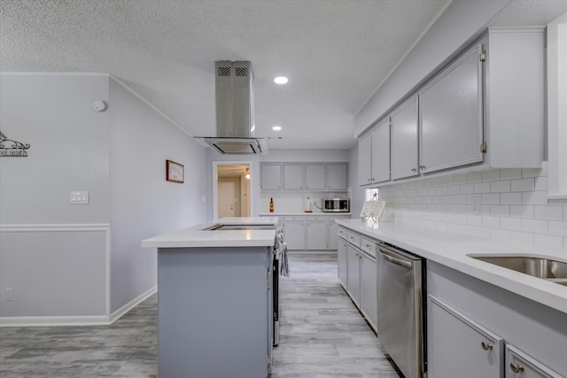 kitchen featuring island range hood, appliances with stainless steel finishes, decorative backsplash, a kitchen island, and light hardwood / wood-style flooring